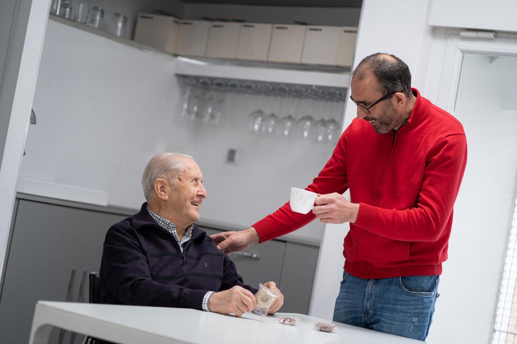 Un hombre mayor con su asistente personal que le da una taza