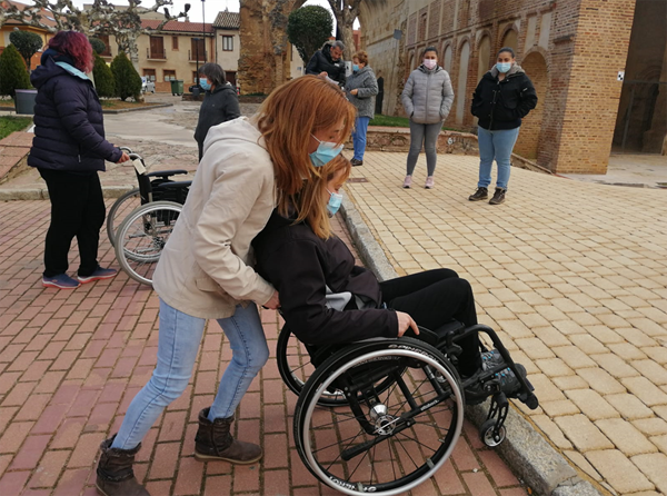 Una mujer llevando a otra en silla de ruedas en una clase práctica
