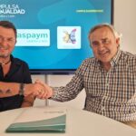 Dándose la mano con una pantalla a sus espaldas con los logos de ASPAYM CyL, Polio CyL e IMPULSA IGUALDAD CyL y el hashtag #IMPULSADERECHOS, a la izquierda: Francisco Sardón, director ejecutivo de ASPAYM CyL, y a la derecha: José Luis Guerrero, presidente de Polio CyL.