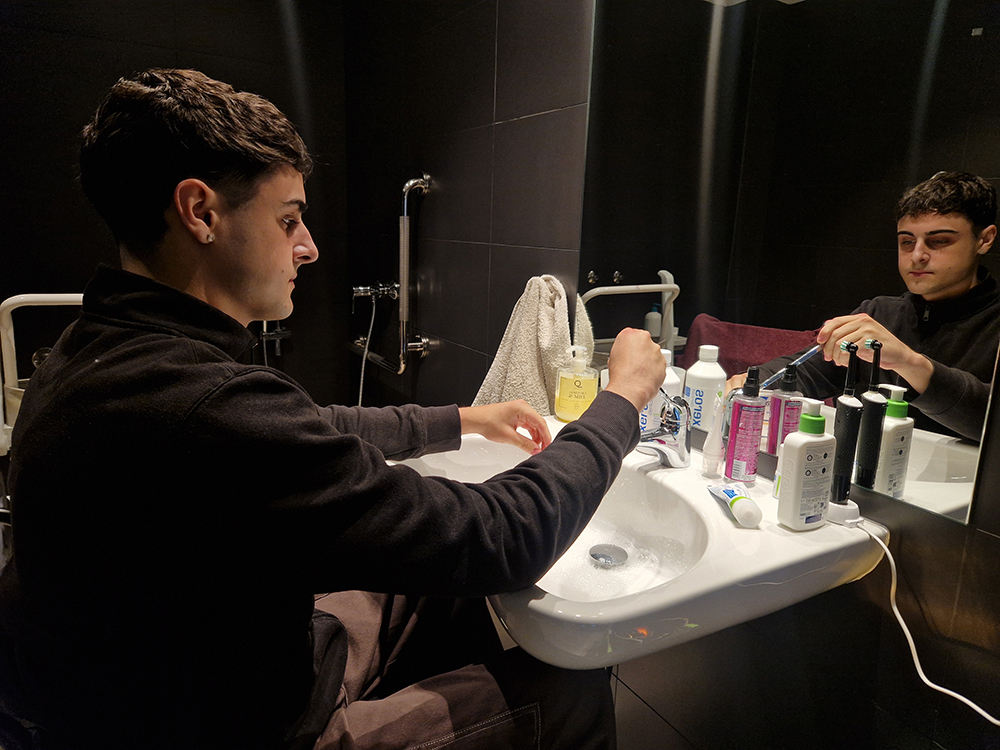 Eloy lavándose las manos en el baño en un lavabo adaptado.