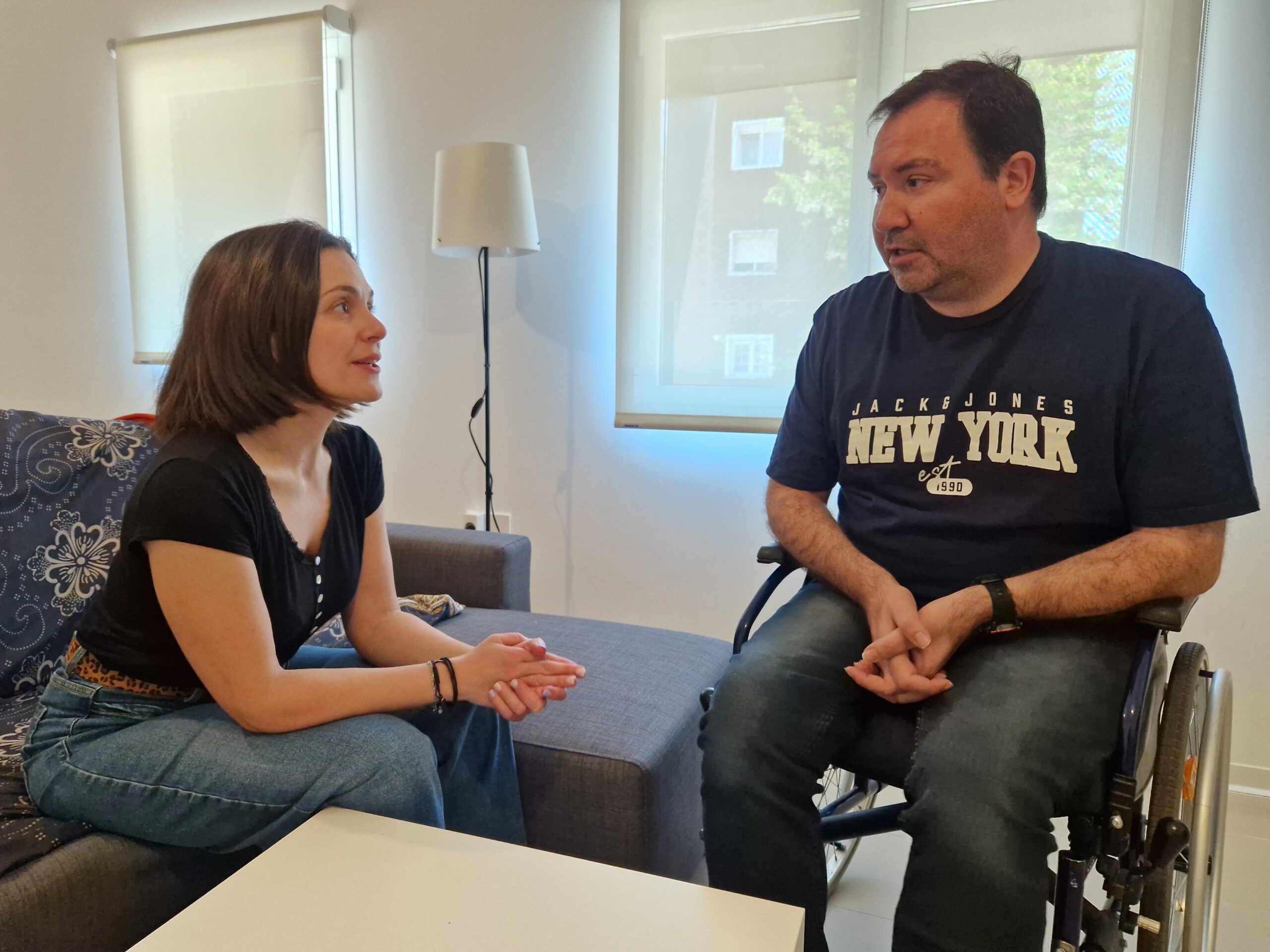 La responsable del SIAP y del proyecto 'Viviendas de transición a la vida independiente', Laura Cano, charla en el salón de uno de los pisos accesibles, con Miguel Ángel San José, uno de los participantes.