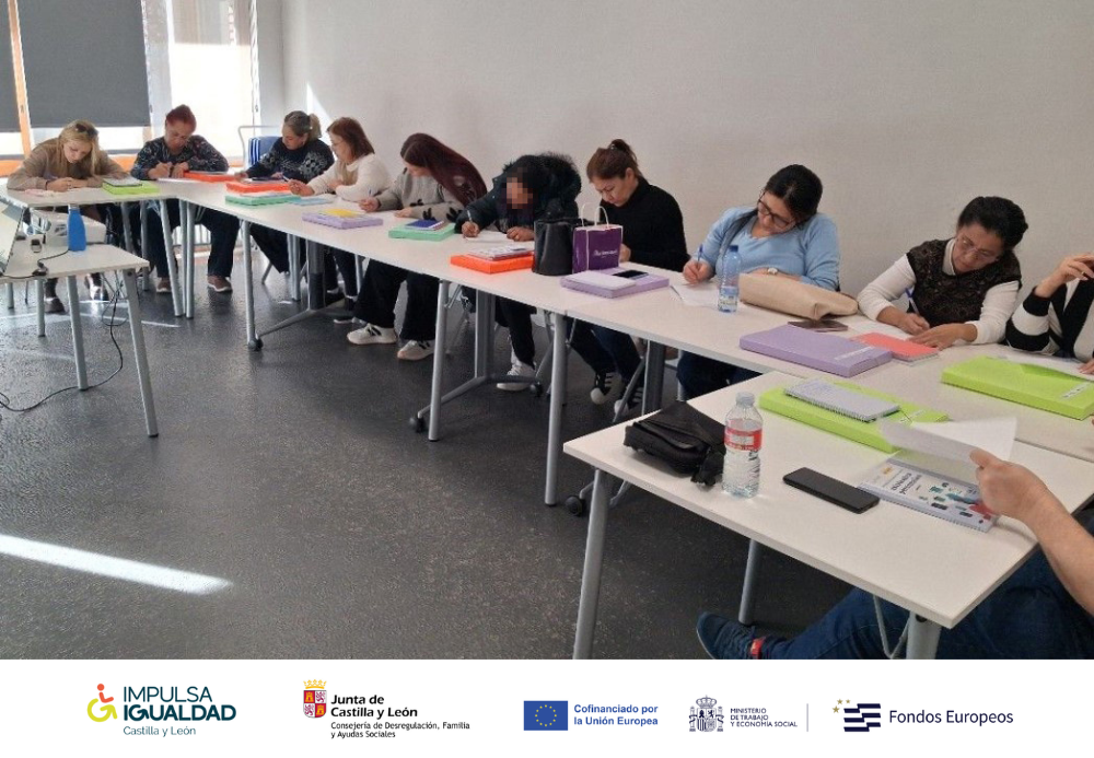 Foto del grupo de participantes trabajando en el aula y abajo, la tira de logos: IMPULSA IGUALDAD CyL, Consejería de Desregulación, Familia y Ayudas Sociales y Fondos Europeos.